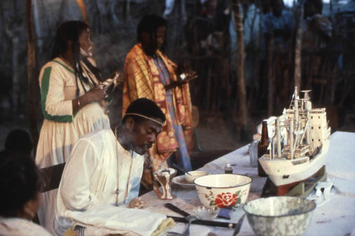 A spirit possession ceremony in South-western Madagascar in which the person possessed has been invaded by the spirit of a French sailor whose dress he imitates. The model ship before him at once embodies the idea of the voyaging spirit and the actual vessel by which Europeans invaded (J.Marre,1990)